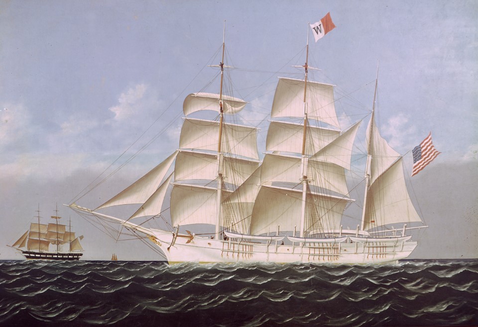 Artwork of the whaling ship The Wanderer sailing on open waters with full sails. The ship features an American flag at the stern and a company flag with a 'W' on the mainmast. A smaller vessel can be seen in the background under a light blue sky with a few clouds.